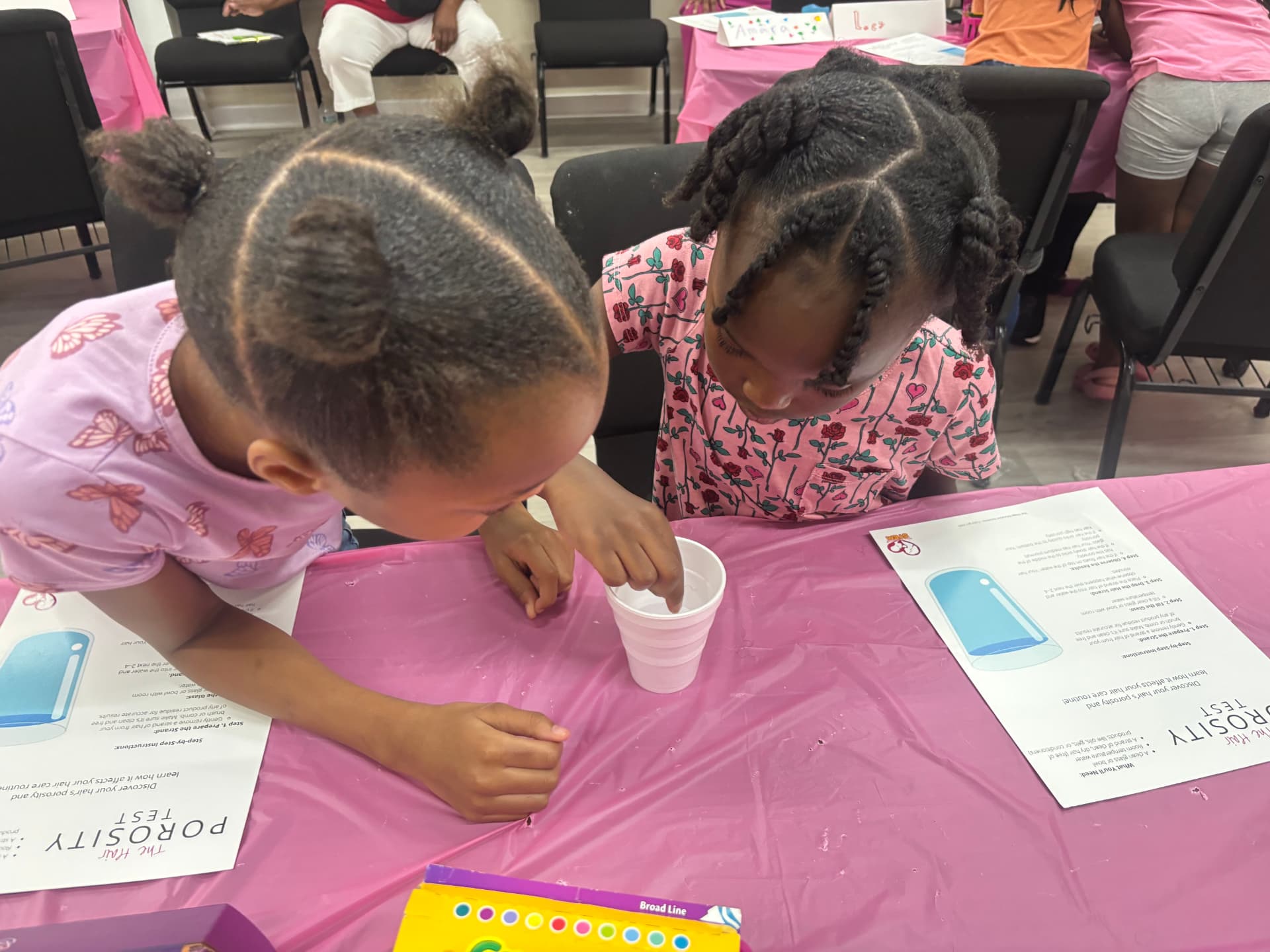 Two young girls running a hair porosity water test during a STEM session